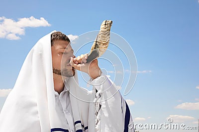 Jewish man in tallit blowing shofar outdoors. Rosh Hashanah celebration Stock Photo