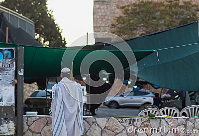 A Jewish man wrapped in a tallit prays outside the synagogue on Sukkot Editorial Stock Photo