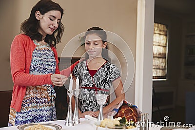 Jewish mother and daughter lighting candles for Shabbat meal Stock Photo