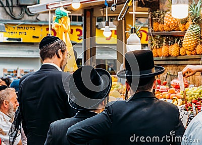 Jewish ultra-orthodox people inspect pineapples at Jerusalem`s Shruk Machane Yehuda market, which has over 250 food stalls offeri Editorial Stock Photo