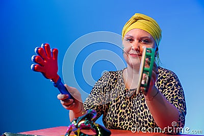 A Jewish woman in a headdress with a painted magen david face leads the noise on Purim while reading Stock Photo
