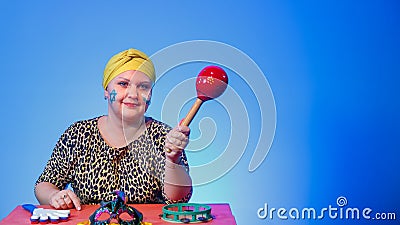 A Jewish woman in a headdress with a painted Magen David face leads the noise on Purim while reading the scroll with a Stock Photo