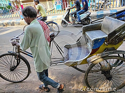 Jhargram, West Bengal, India - May 05, 2019: A hand pulled rickshwa was pulled by someone on a busy road of a city in West Bengal Editorial Stock Photo