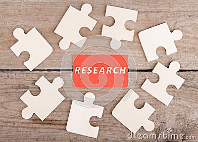Jigsaw Puzzle Pieces with text & x22;Research& x22; on wooden background Stock Photo