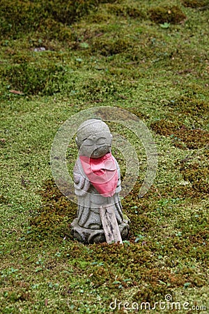 A Jizo statue standing in the moss-covered garden. Editorial Stock Photo