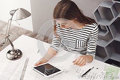 Job, career and business concept. Portrait of young fashionable professional female designer sitting at table, looking Stock Photo