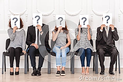 Job Interview. Candidates sitting waiting holding papers with quaestion mark choice Stock Photo