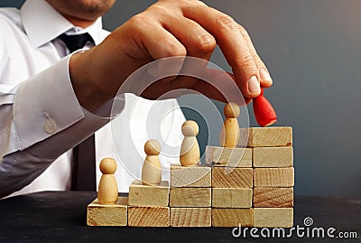 Job Promotion. Manager is holding figurine near career ladder. Stock Photo