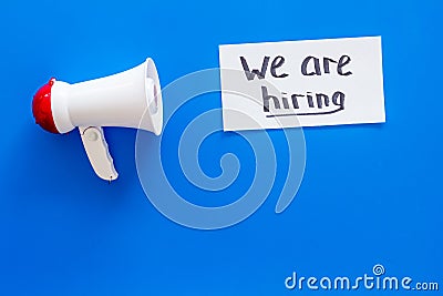 Job recruiting advertisement. We are hiring lettering near megaphone on blue background top view copy space Stock Photo