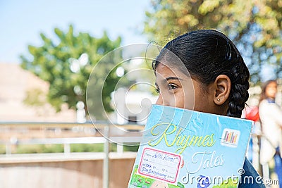 Jodhpur, Rajasthan, India - Jan 10th 2020: Closeup of indian happy student school girl holding exercise notebook cover her face, Editorial Stock Photo