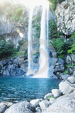 Joengbang waterfall with lens flare from sunlight in Seogwipo, Jeju Island, South Korea Stock Photo