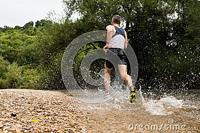 Jogger running through a streambed Stock Photo