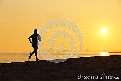 Jogger silhouette running on the beach at sunset Stock Photo