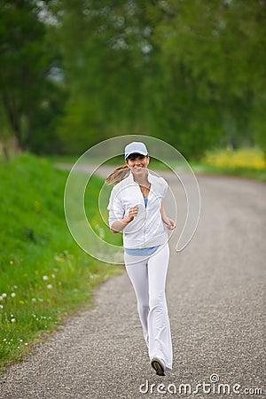 Jogging - sportive woman running on road in nature Stock Photo