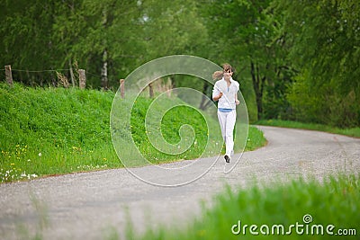 Jogging - sportive woman running on road in nature Stock Photo