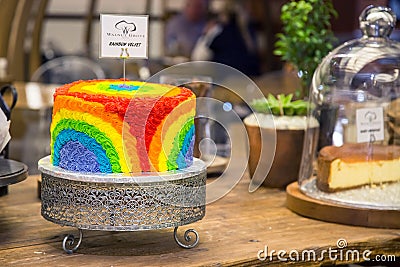 Rainbow coloured cake on display. Brightly coloured icing. Editorial Stock Photo