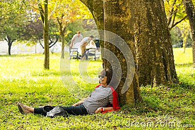 Middle aged lady lying against a tree at The Winter Sculpture Fa Editorial Stock Photo