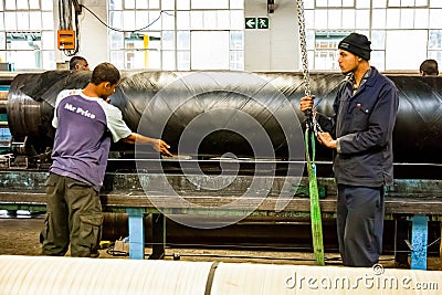 Diverse workers inside a rubber and pipe fabrication assembly line in a factory Editorial Stock Photo