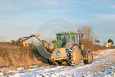 John deere tractor cutting hedges in snow Editorial Stock Photo