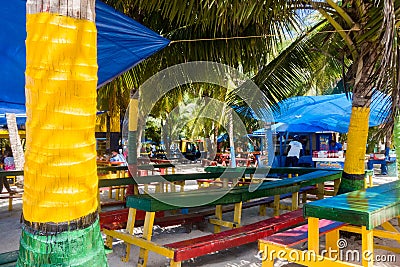 JOHNNY CAY, COLOMBIA - OCTOBER 21, 2017: Close up of some typical wooden tables with the color of colombian flag Editorial Stock Photo