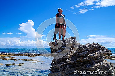 JOHNNY CAY, COLOMBIA - OCTOBER 21, 2017: Unidentified blonde woman enjoying the beautiful sunny day over a rock in the Editorial Stock Photo