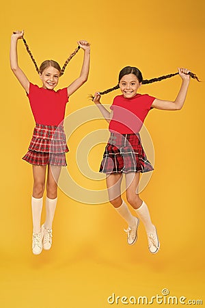 Join celebration. School uniform. Scottish style. Cheerful friends schoolgirls jumping yellow background. Celebrate Stock Photo