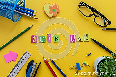 JOIN US - CONCEPT text on yellow work place, office background with supplies Stock Photo