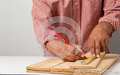 Joiner measuring a wooden plank with tape measure yellow on the work-table for construction, carpenter Use tool checking accuracy Stock Photo