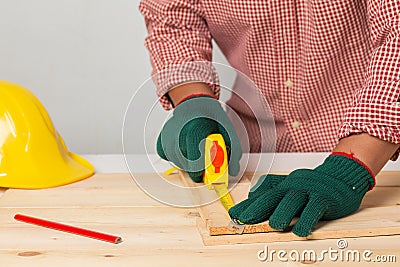 joiner measuring a wooden plank with tape measure yellow on the work-table for construction, carpenter Use tool checking accuracy Stock Photo