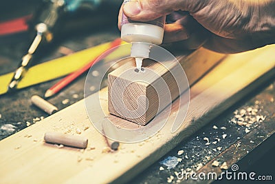 Joinery - joiner put the glue into a drilled hole for wooden dowel joint Stock Photo