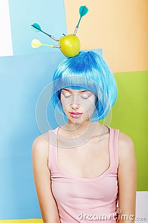 Joke. Eccentric Woman Oddball in Blue Wig with Darts and Green Apple Stock Photo