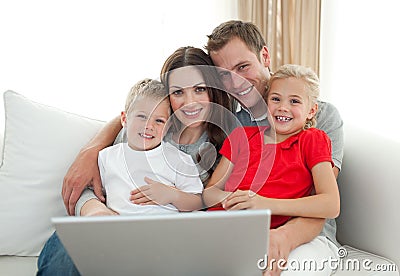 Jolly family using a computer sitting on sofa Stock Photo