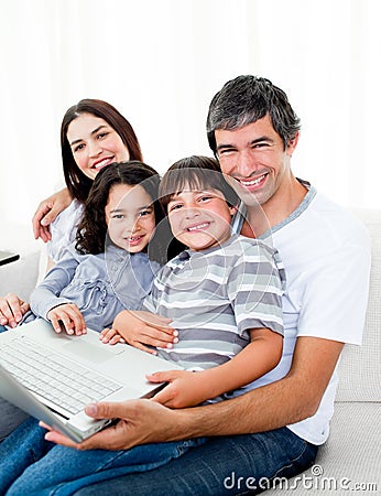 Jolly family using a laptop sitting on sofa Stock Photo