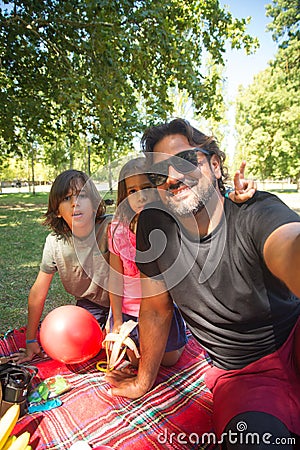 Jolly father with disability taking selfie with kids on picnic Stock Photo