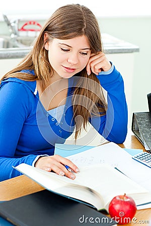 Jolly female teenager studying in the kitchen Stock Photo