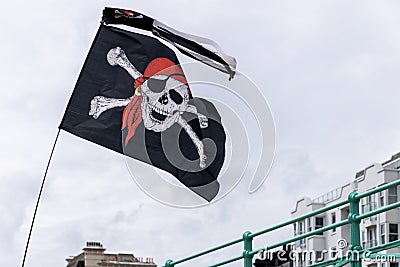 Jolly Roger flag flying in the wind above Brighton sea front Editorial Stock Photo