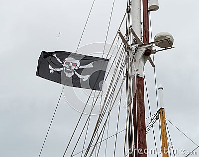 Jolly Roger / Pirate flag Skull and crossbones flying from mast of a sailing ship. Editorial Stock Photo