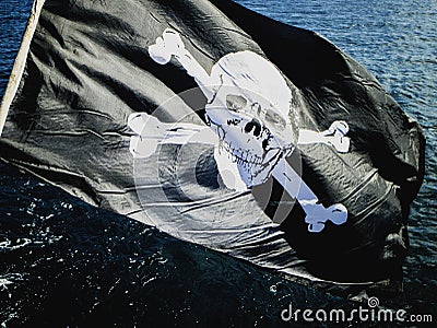 Jolly Rogers pirate flag flying from a sailing boat Stock Photo