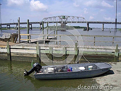 Jon boat with crab traps tied to dock and pushed up on boat land Stock Photo