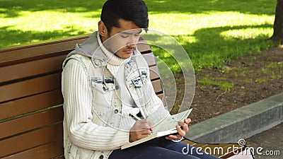 Jonge mens die iets in notitieboekje schrijven stock footage Jonge mens die iets in notitieboekje schrijven stock footage