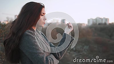 Jonge vrouw die verwarmen in de herfst Koude dalingsdag Vrouwenvorst op zonsondergang op straat met stadsachtergrond stock footage Jonge vrouw die verwarmen in de herfst Koude dalingsdag Vrouwenvorst op zonsondergang op straat met stadsachtergrond stock footage