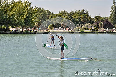 kids on a stand paddle on the pond of the leisure center of Jonzac Editorial Stock Photo