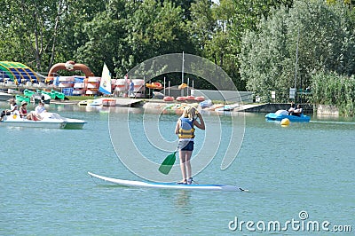 kids on a stand paddle on the pond of the leisure center of Jonzac Editorial Stock Photo