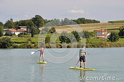 JONZAC,FRANCE-AUGUST 01, 2017: kids on a stand paddle on the pond of the leisure center of Jonzac Editorial Stock Photo