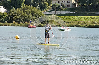 Kids on a stand paddle on the pond of the leisure center of Jonzac Editorial Stock Photo