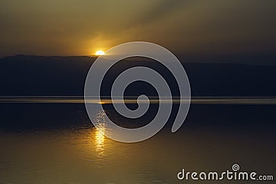 Jordan. Dead Sea. Calm at sea. Sunset on Dead Sea coast. Orange sun is reflected in water. There is light path in water Stock Photo