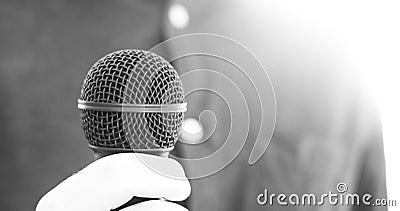 Journalist is holding a microphone in the foreground, blurry background Stock Photo