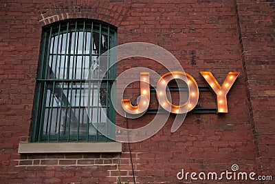 JOY Light Bulb Sign on Wall Stock Photo