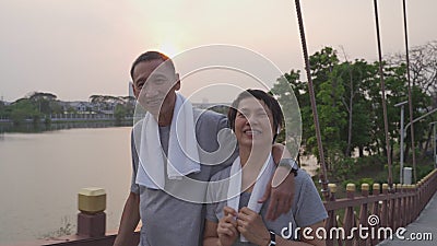 Joyeux couple senior main tendue et exercice de marche au parc le soir au coucher du soleil. smiley active asiatique amateur âgé a banque de vidéos Joyeux couple senior main tendue et exercice de marche au parc le soir au coucher du soleil. smiley active asiatique amateur âgé a banque de vidéos