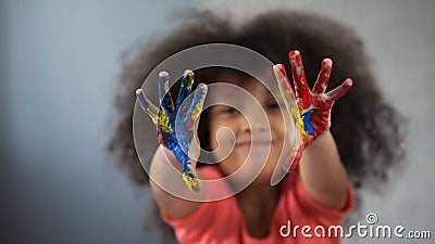 Joyful African female child having fun and showing painted palms into camera Stock Photo